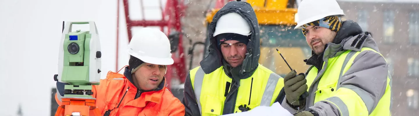Travailleurs portant des gilets de sécurité et des casques de sécurité sur un chantier de construction en hiver