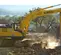 Excavatrice Kobelco jaune et grise creusant des roches et de la terre sur un chantier