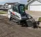 Chargeuse à chenilles compacte BOBCAT blanche, rouge et noire creusant de la terre