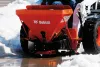 Épandeur Bobcat rouge monté sur une chargeuse à direction à glissement dans la neige