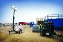 light towers at a jobsite with a man working on a pump