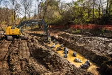 Excavatrice John Deere jaune creusant la terre